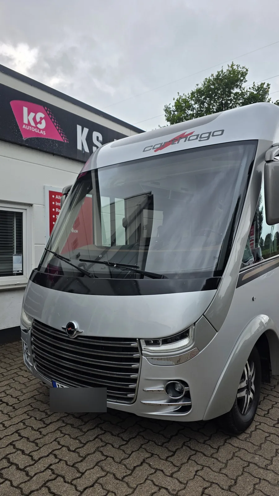 Carthago-Wohnmobil von vorn vor dem Eingang des KS Autoglas Zentrums