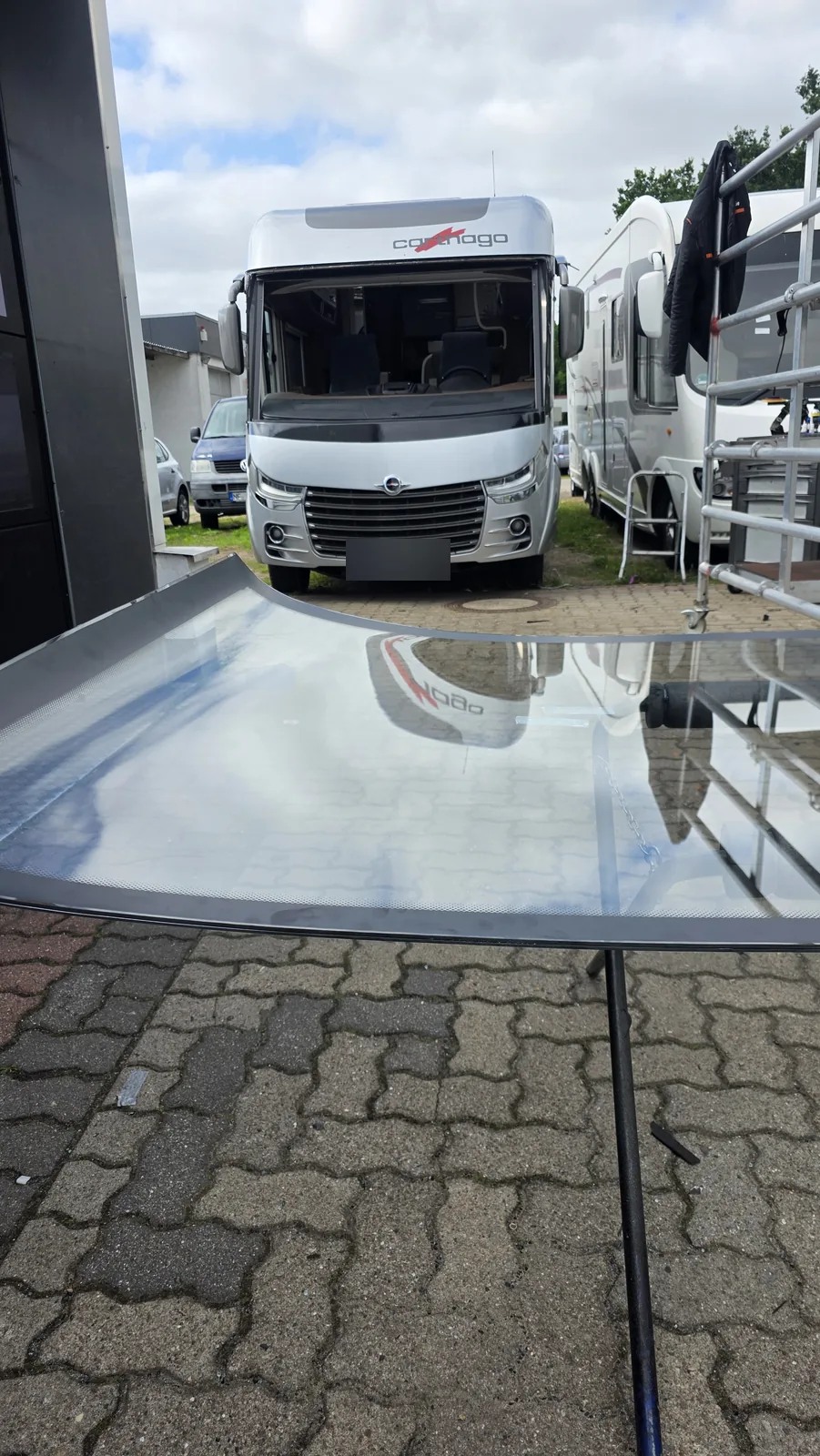 Neue Wohnmobil-Frontscheibe liegt bereit, dahinter der Carthago ohne Scheibe