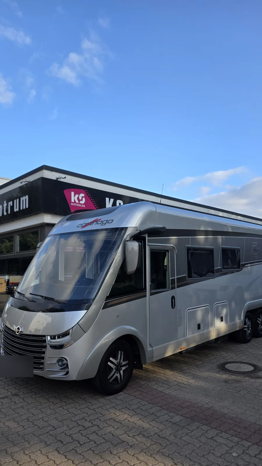 Carthago-Wohnmobil im Sonnenschein vor dem KS Autoglas Zentrum in Elmshorn