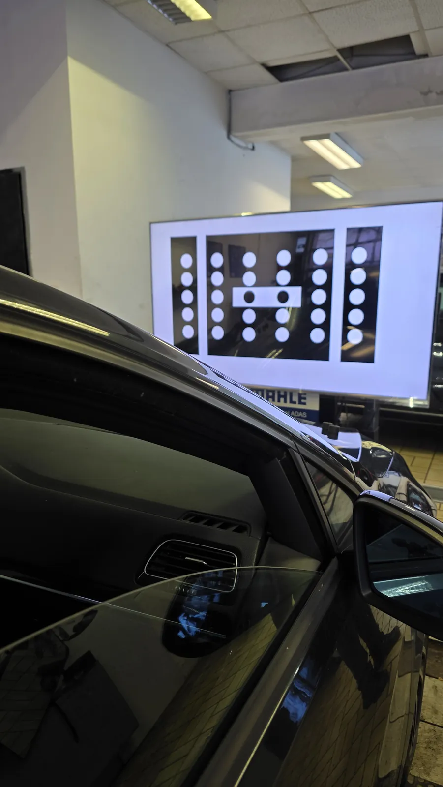 Kalibriertafel für die Frontkamera vor einem schwarzen Pkw in der Werkstatt von KS Autoglas Elmshorn