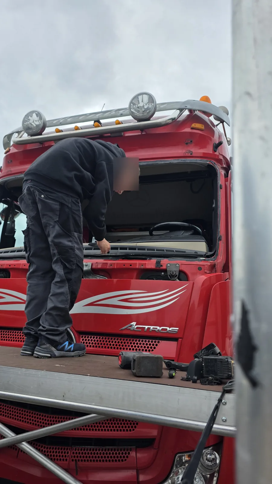Monteur von KS Autoglas baut auf dem Montagegerüst die Frontscheibe eines Mercedes Actros aus