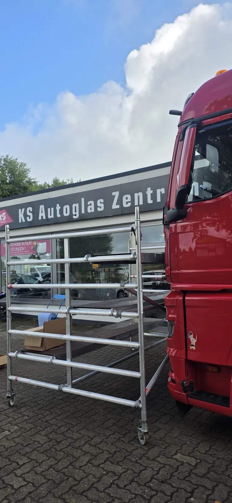Rotes Lkw-Fahrerhaus und Montagegerüst vor dem KS Autoglas Zentrum in Elmshorn