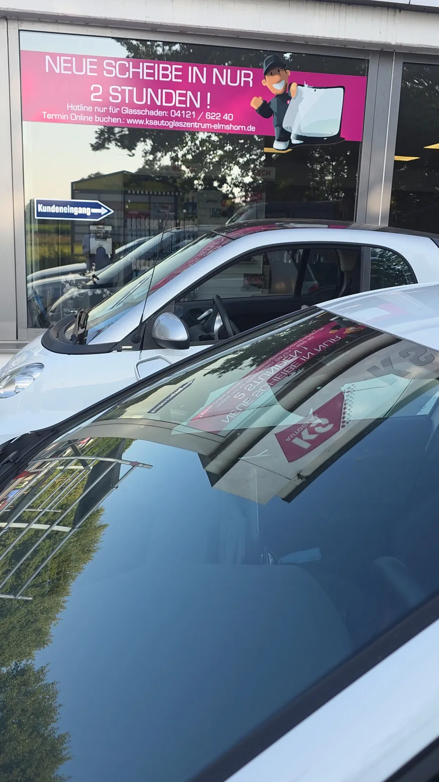 Das Schaufenster des KS Autoglas Zentrums spiegelt sich in der Frontscheibe eines Pkw