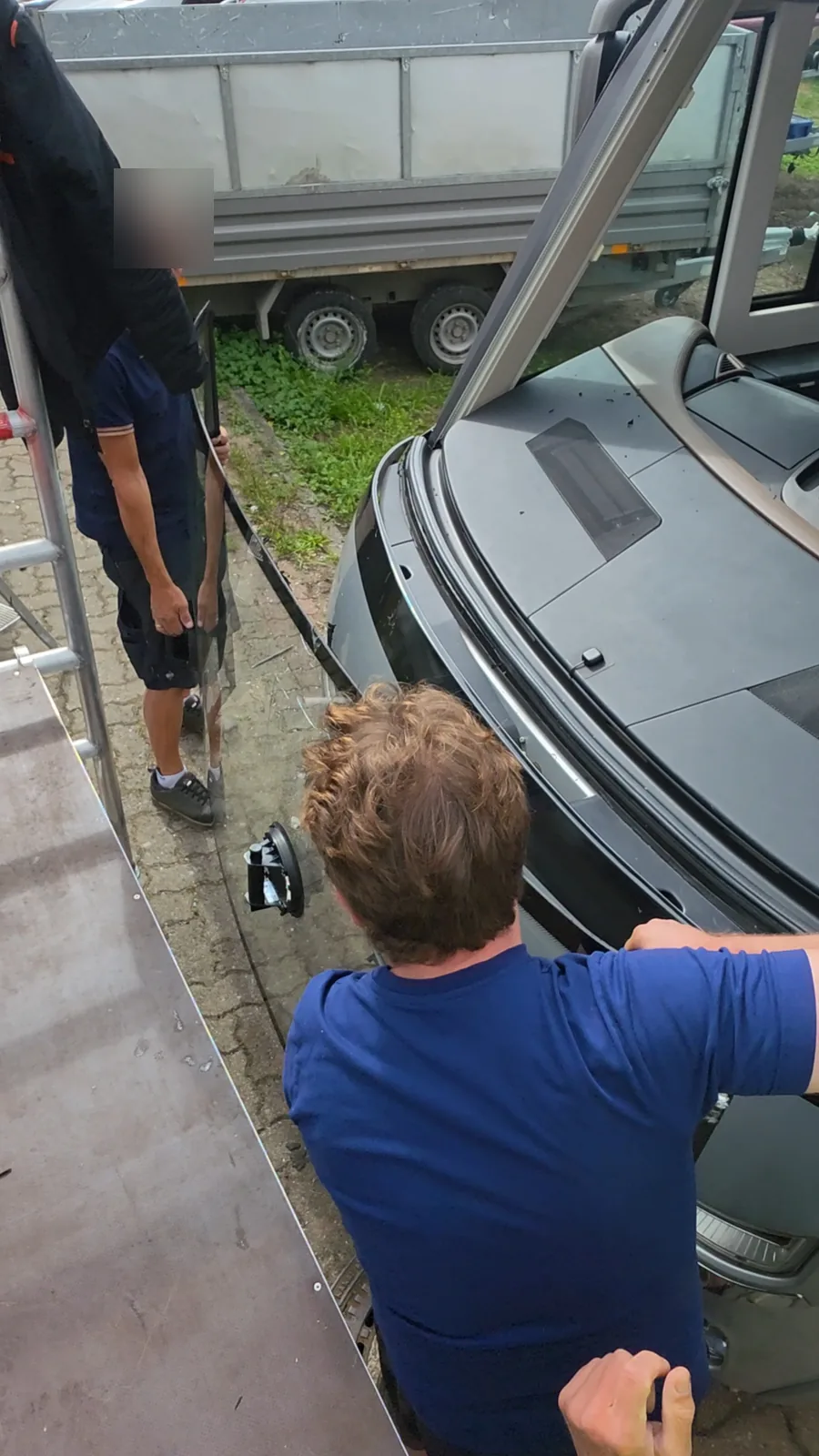 Zwei Monteure setzen mit Saugheber die neue Frontscheibe in ein Wohnmobil ein